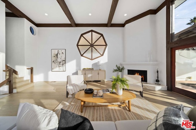 living room featuring a fireplace, light hardwood / wood-style flooring, and beamed ceiling