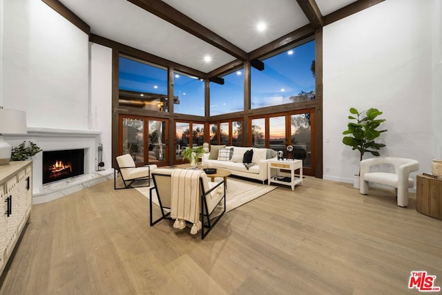 living room with beam ceiling, light wood-type flooring, a fireplace, and french doors