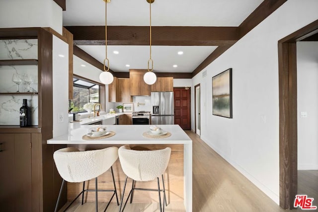 kitchen with light hardwood / wood-style floors, pendant lighting, a kitchen bar, kitchen peninsula, and stainless steel appliances