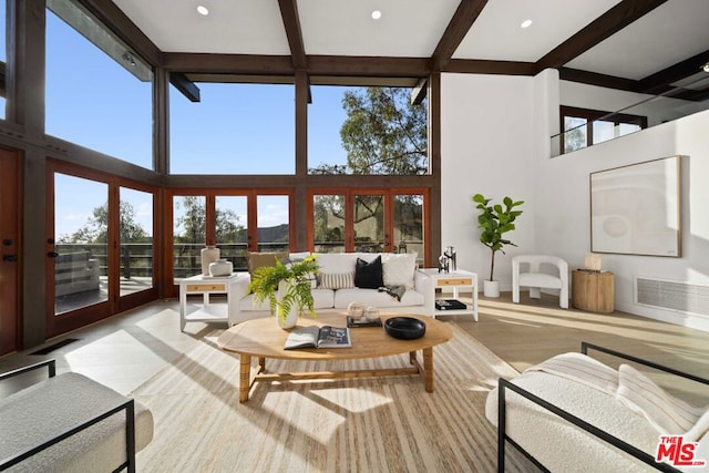 living room with light wood-type flooring, french doors, a towering ceiling, and beamed ceiling