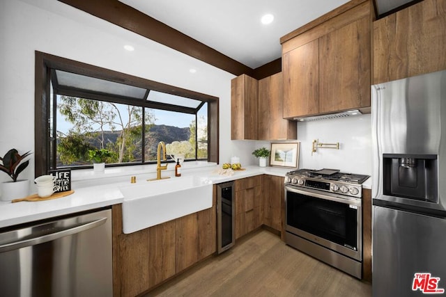 kitchen featuring stainless steel appliances, wine cooler, hardwood / wood-style floors, and sink