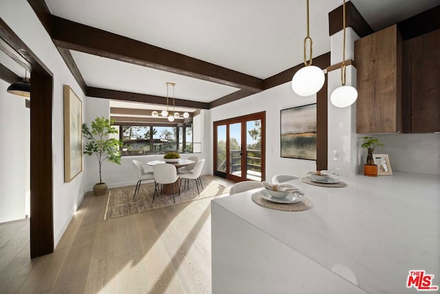 dining room with light hardwood / wood-style floors, a notable chandelier, beam ceiling, and french doors