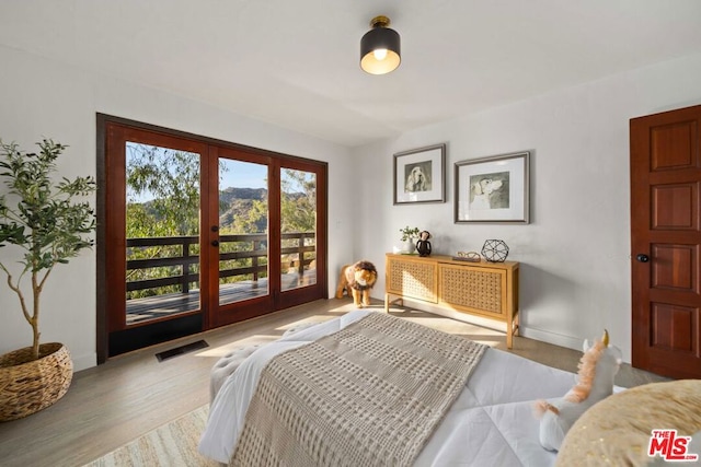 bedroom with french doors, multiple windows, and light hardwood / wood-style flooring