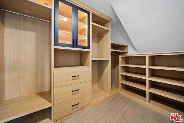 walk in closet with vaulted ceiling and hardwood / wood-style floors