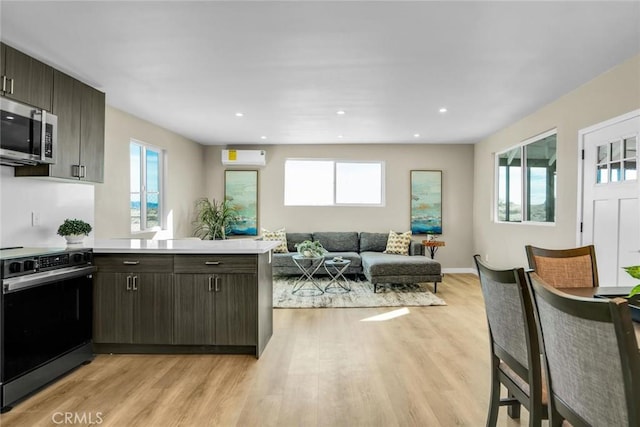 kitchen featuring dark brown cabinets, electric range, light hardwood / wood-style floors, and kitchen peninsula