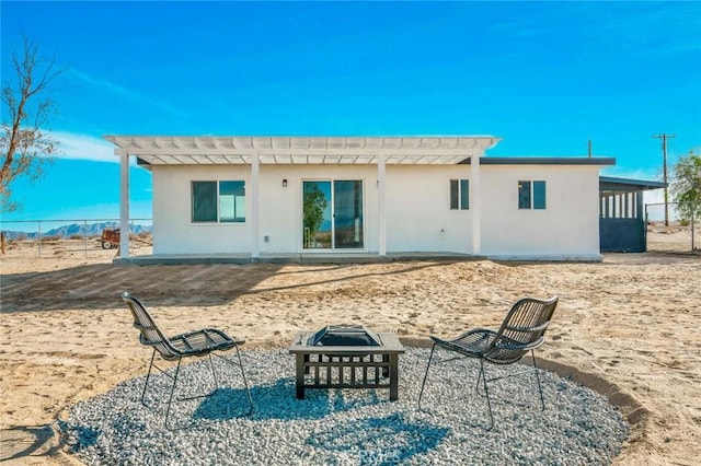 back of property with an outdoor fire pit and a pergola