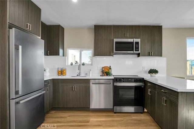 kitchen with stainless steel appliances, sink, dark brown cabinetry, and kitchen peninsula