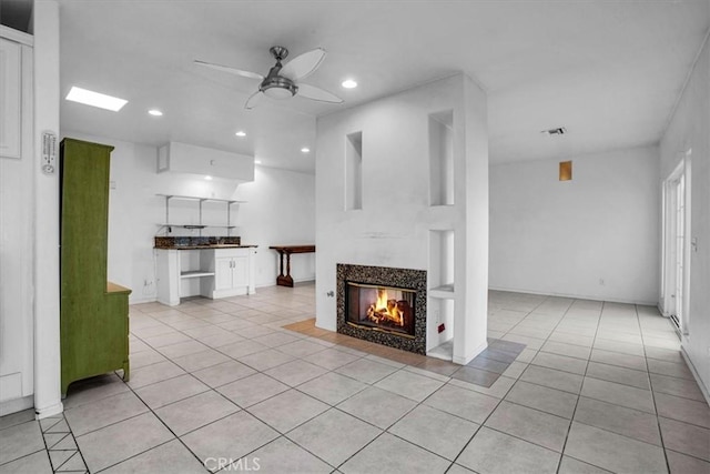 unfurnished living room featuring ceiling fan, light tile patterned flooring, and a multi sided fireplace