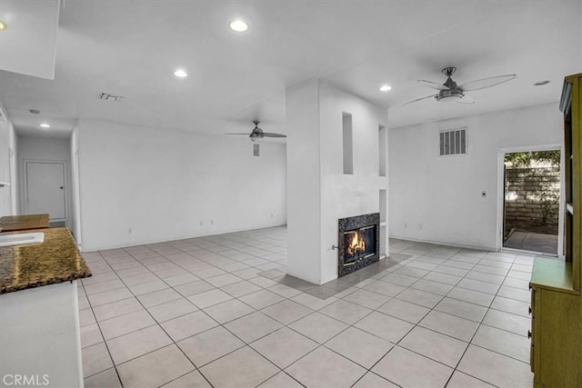 unfurnished living room with ceiling fan, sink, and light tile patterned floors