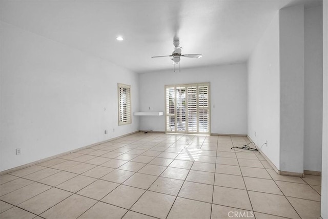 tiled empty room featuring ceiling fan