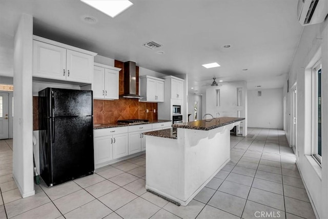 kitchen with white cabinetry, appliances with stainless steel finishes, a kitchen breakfast bar, wall chimney exhaust hood, and a center island