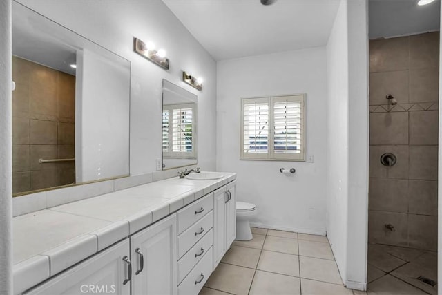 bathroom with toilet, vanity, and tile patterned flooring