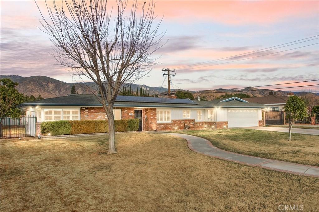 ranch-style house with a garage, a mountain view, and a yard