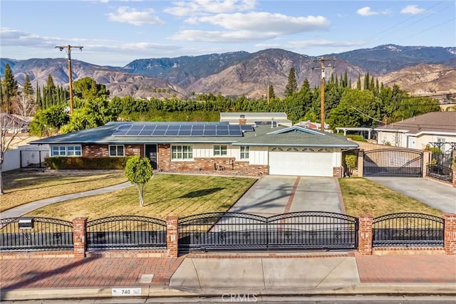 ranch-style house featuring a garage, a front yard, a mountain view, and solar panels