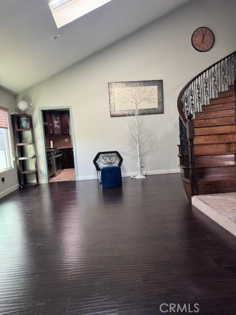 unfurnished room featuring vaulted ceiling with skylight, wood finished floors, baseboards, and stairs