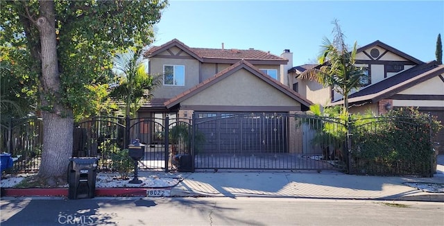 view of front facade featuring a fenced front yard, an attached garage, driveway, a gate, and stucco siding