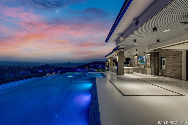 pool at dusk featuring a bar