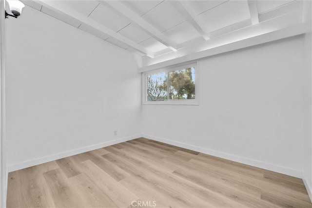 empty room with light hardwood / wood-style floors and beamed ceiling