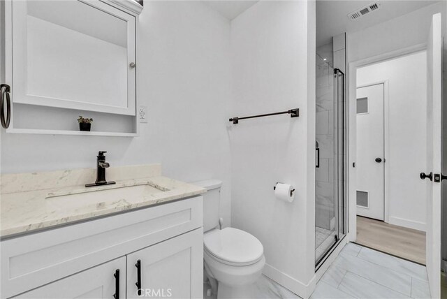 bathroom with toilet, a shower with door, and vanity