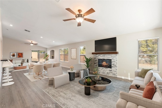 living room featuring ceiling fan, light hardwood / wood-style flooring, a fireplace, and lofted ceiling