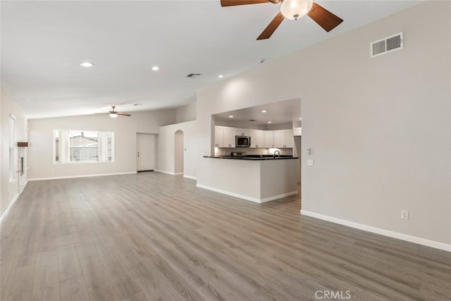 unfurnished living room with ceiling fan, light hardwood / wood-style flooring, and lofted ceiling