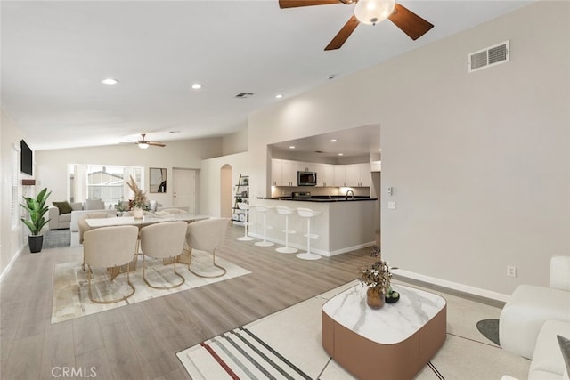 living room with light wood-type flooring, ceiling fan, and lofted ceiling