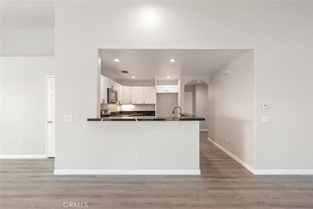 kitchen with sink, wood-type flooring, white cabinets, and kitchen peninsula