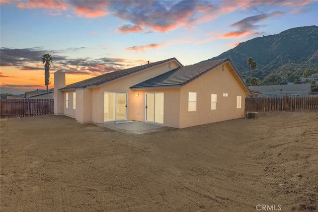 back house at dusk featuring a mountain view, a patio, and central air condition unit