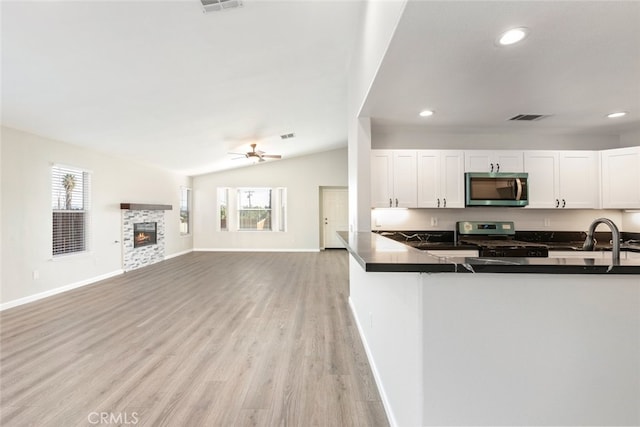 kitchen with kitchen peninsula, appliances with stainless steel finishes, sink, white cabinetry, and lofted ceiling