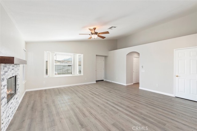 unfurnished living room featuring ceiling fan, light hardwood / wood-style flooring, vaulted ceiling, and a fireplace