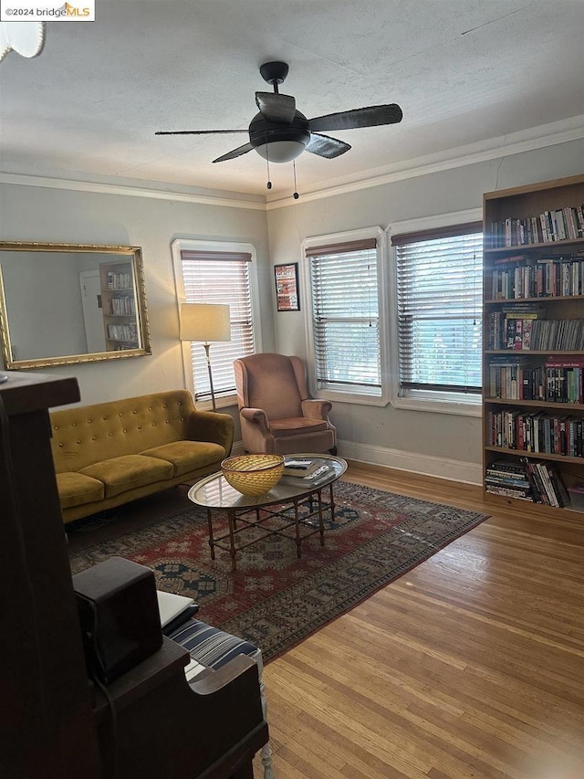 living room featuring hardwood / wood-style flooring, a textured ceiling, ornamental molding, and ceiling fan