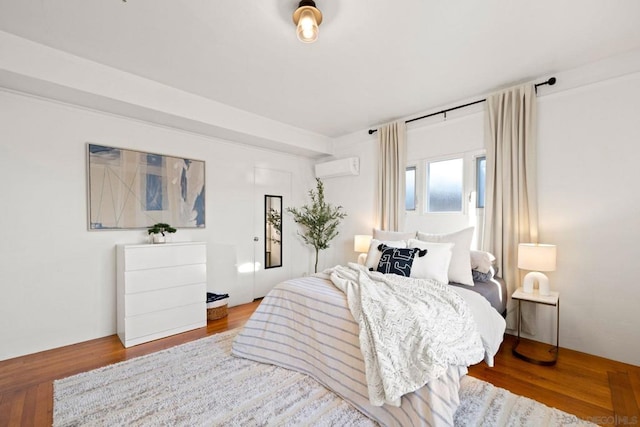 bedroom featuring a wall mounted AC and hardwood / wood-style flooring