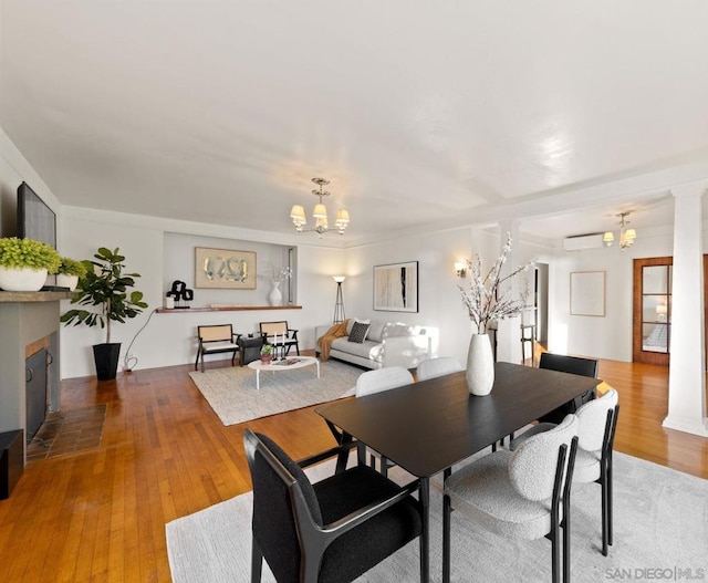 dining area with light hardwood / wood-style floors, an AC wall unit, and an inviting chandelier