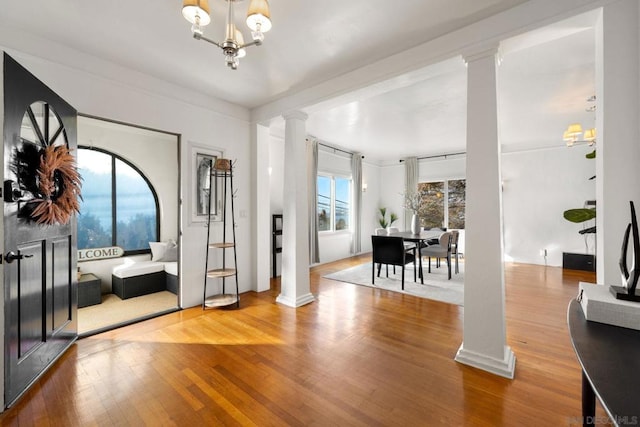 foyer featuring hardwood / wood-style floors, ornate columns, and a notable chandelier