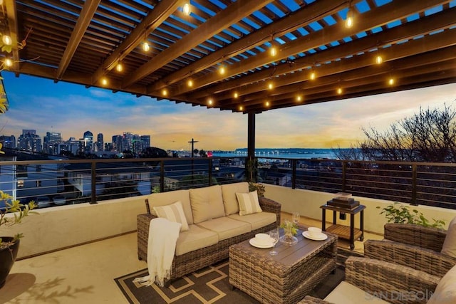 patio terrace at dusk featuring outdoor lounge area and a balcony