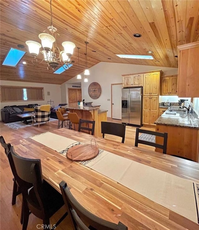 dining room with wooden ceiling, lofted ceiling with skylight, sink, and a notable chandelier