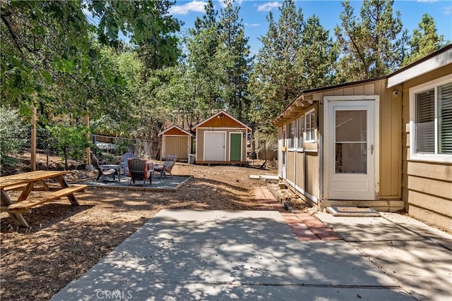 view of yard featuring a storage unit, a patio, and a fire pit