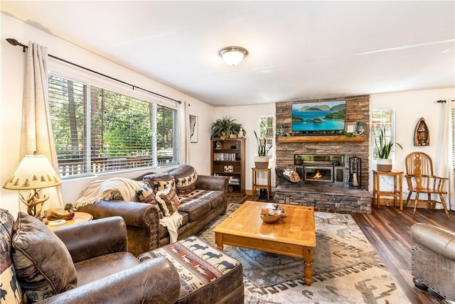 living room with dark hardwood / wood-style floors and a stone fireplace