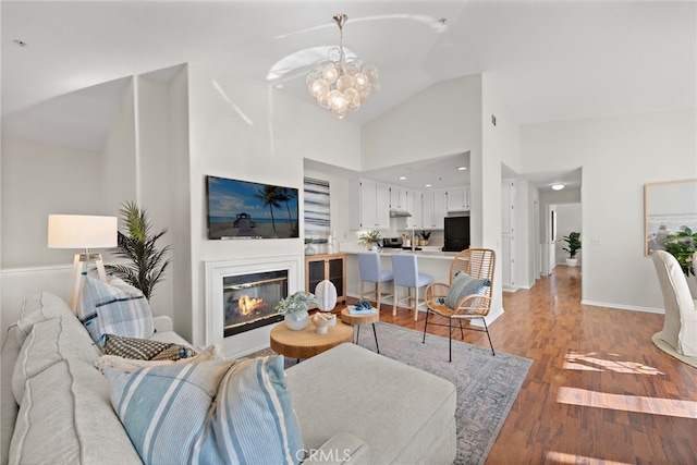 living room with lofted ceiling, an inviting chandelier, and hardwood / wood-style flooring