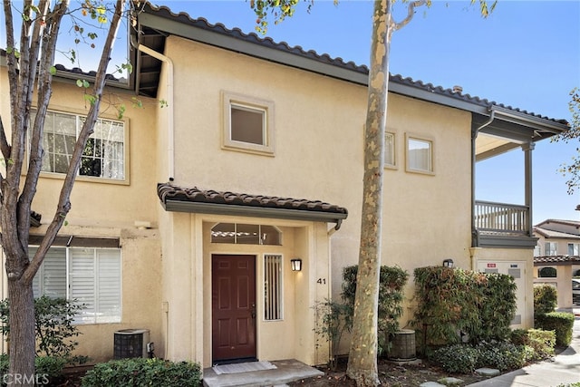 view of front of home featuring cooling unit and a balcony