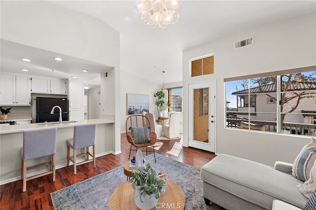 living room featuring vaulted ceiling, dark hardwood / wood-style flooring, a chandelier, and sink