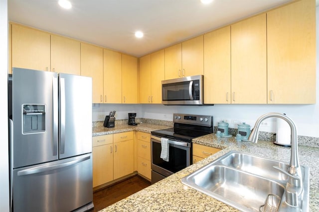 kitchen with appliances with stainless steel finishes, dark hardwood / wood-style floors, light brown cabinetry, light stone counters, and sink