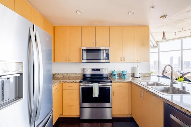 kitchen featuring stainless steel appliances, light brown cabinetry, pendant lighting, and sink