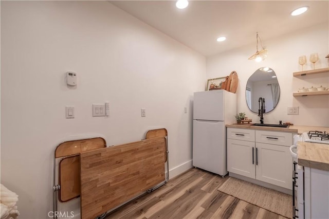 kitchen featuring white fridge, butcher block countertops, gas stove, white cabinets, and sink