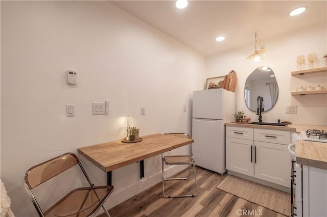 kitchen featuring sink, white appliances, white cabinetry, light hardwood / wood-style flooring, and wood counters