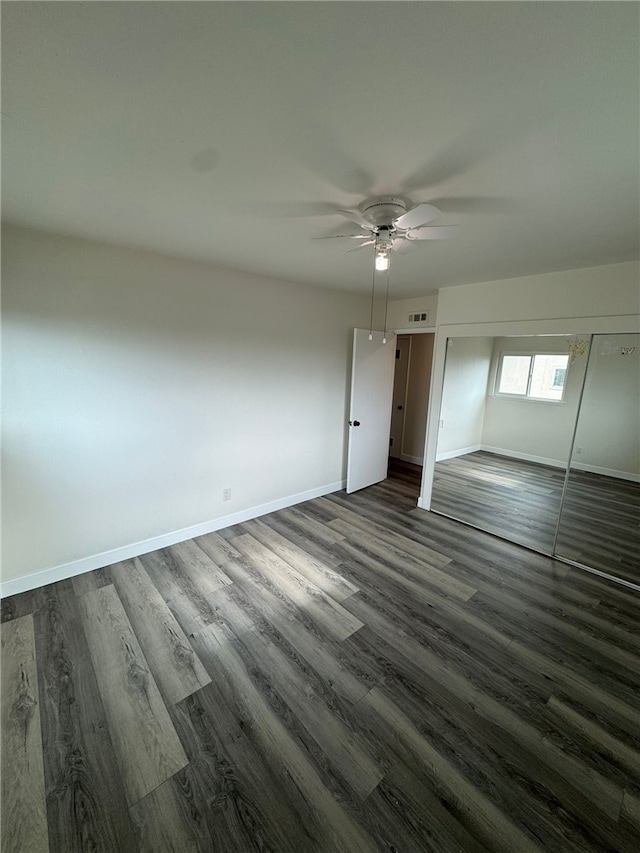 unfurnished bedroom with ceiling fan, a closet, and dark hardwood / wood-style flooring