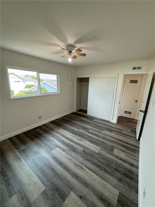 unfurnished bedroom featuring ceiling fan, a closet, and dark wood-type flooring