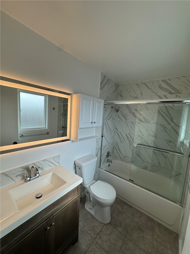 full bathroom featuring combined bath / shower with glass door, vanity, and toilet