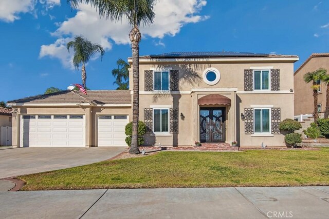 view of front of home with a garage, french doors, a front lawn, and solar panels