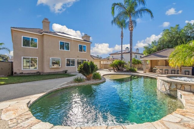 view of swimming pool featuring a patio area, exterior bar, and an in ground hot tub